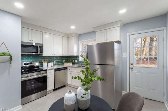 kitchen with white cabinets, stainless steel appliances, light stone counters, and tasteful backsplash