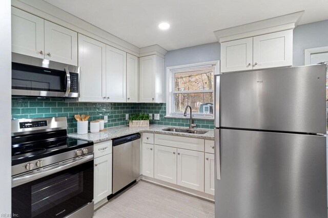 kitchen with white cabinets, sink, decorative backsplash, light stone countertops, and stainless steel appliances