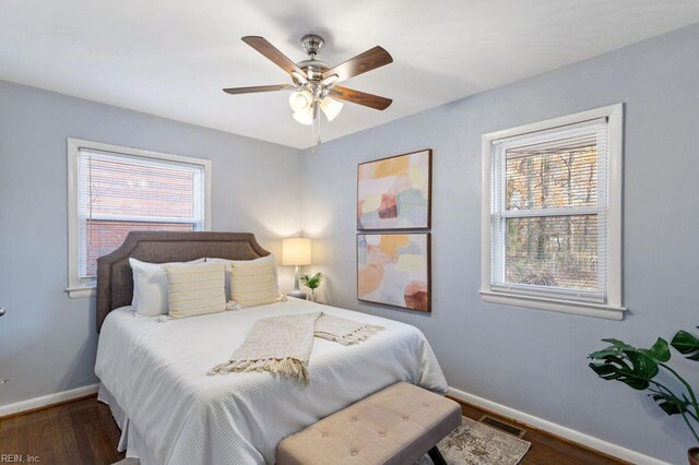 bedroom featuring dark hardwood / wood-style flooring, multiple windows, and ceiling fan