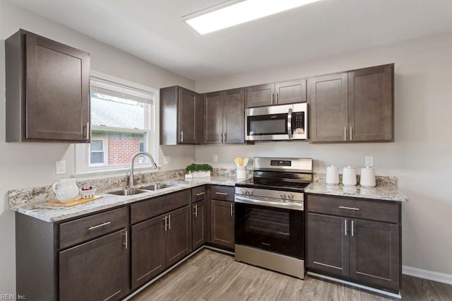 kitchen featuring appliances with stainless steel finishes, light wood-type flooring, and dark brown cabinets