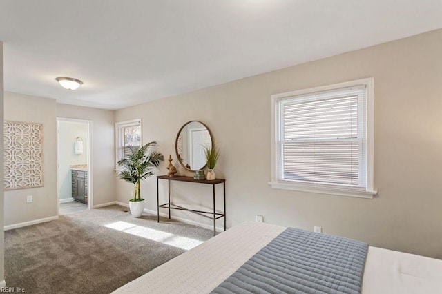 bedroom with ensuite bathroom and light carpet