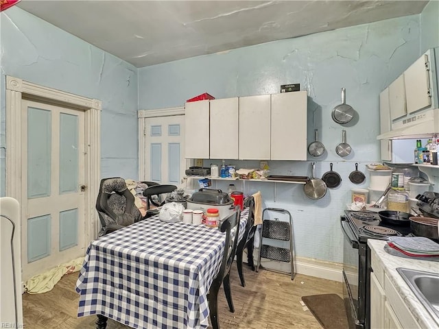 kitchen with white cabinets, light wood-type flooring, and black electric range