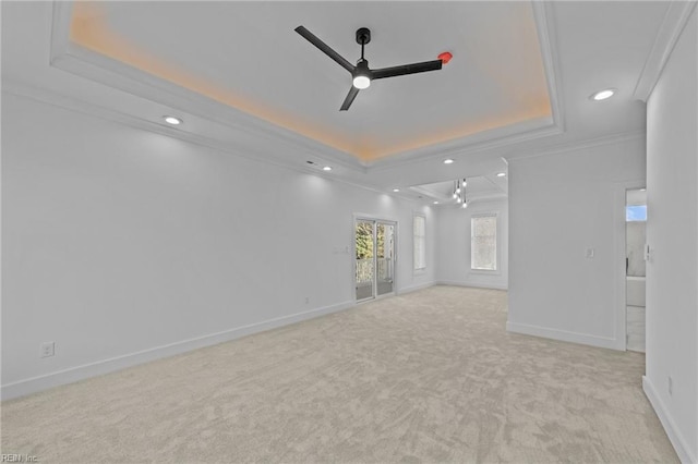 carpeted spare room with a tray ceiling, ceiling fan, and ornamental molding