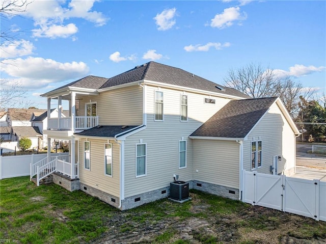 back of property featuring central air condition unit, a balcony, and a lawn