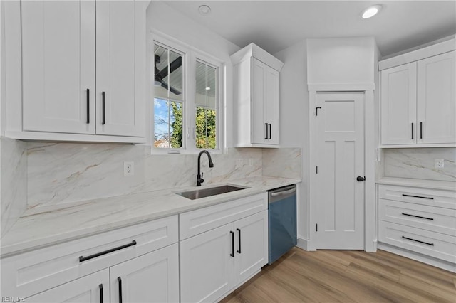 kitchen with sink, stainless steel dishwasher, backsplash, light hardwood / wood-style floors, and white cabinets