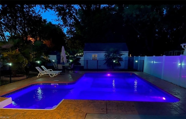 pool at night featuring a patio