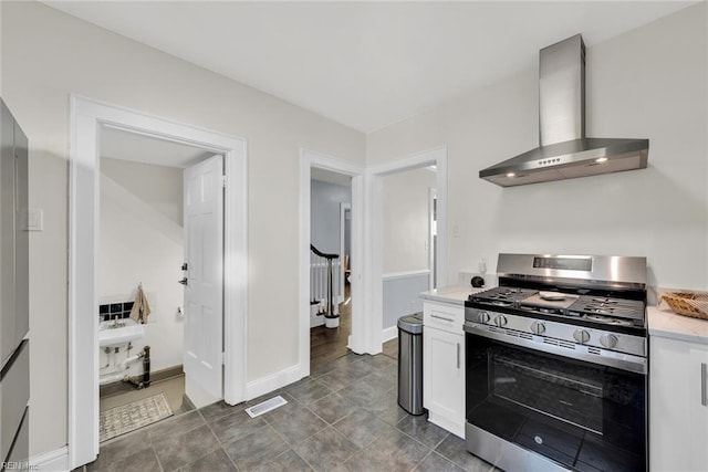 kitchen featuring white cabinets, wall chimney exhaust hood, and stainless steel range with gas stovetop