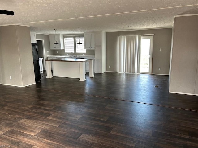 unfurnished living room with dark hardwood / wood-style floors, plenty of natural light, and a textured ceiling