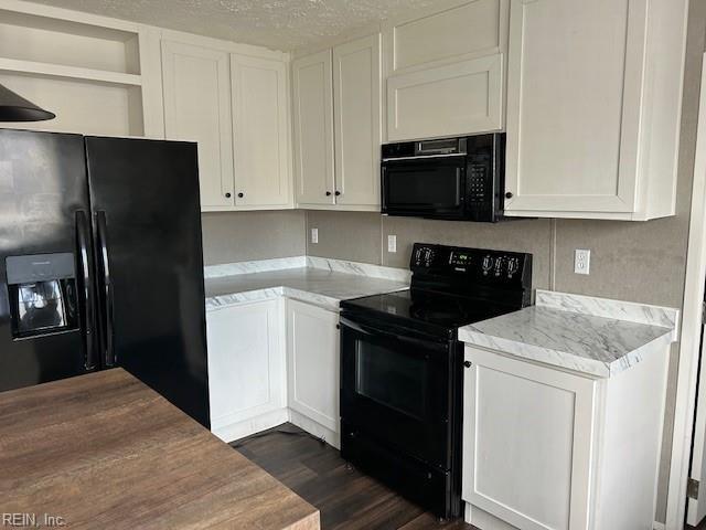 kitchen featuring dark hardwood / wood-style flooring, light stone counters, white cabinetry, and black appliances