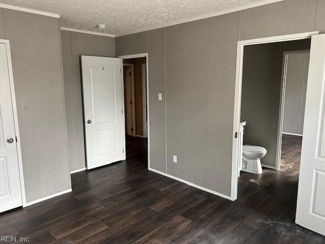 unfurnished bedroom featuring dark hardwood / wood-style flooring, a textured ceiling, and ensuite bath