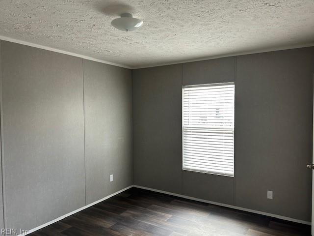 spare room featuring dark hardwood / wood-style floors and a textured ceiling