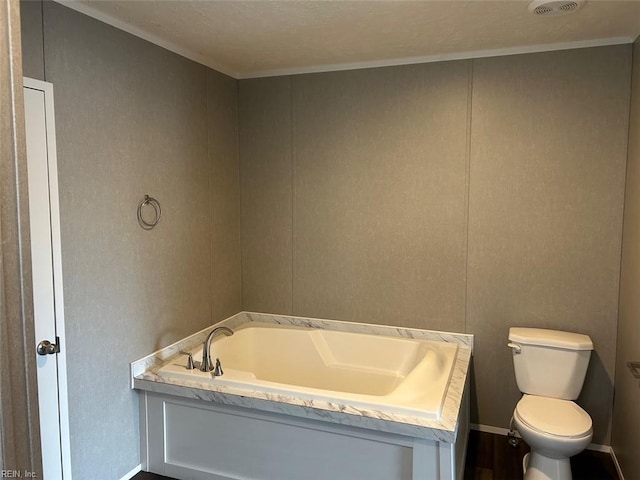 bathroom featuring a textured ceiling, toilet, and a tub