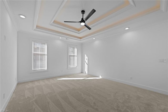 carpeted spare room featuring a raised ceiling, ceiling fan, and ornamental molding