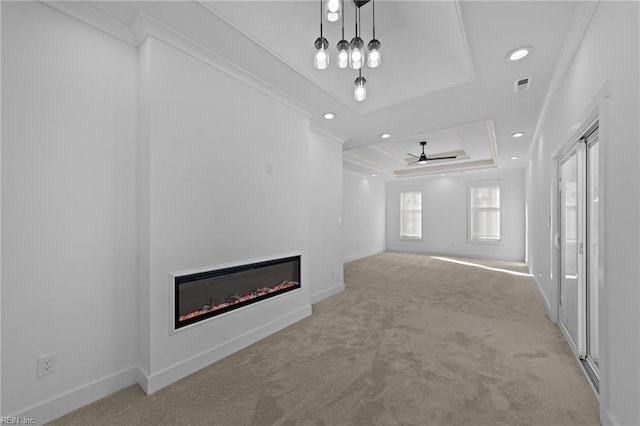 unfurnished living room featuring ceiling fan, a raised ceiling, light colored carpet, and crown molding