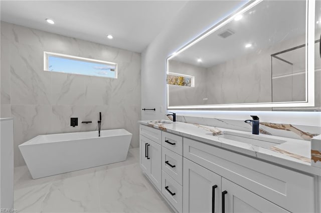 bathroom featuring a tub, vanity, and tile walls