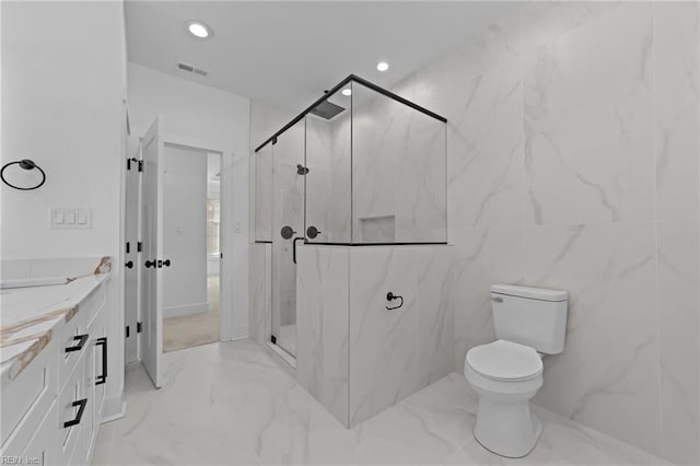 bathroom featuring vanity, toilet, a shower with shower door, and tile walls