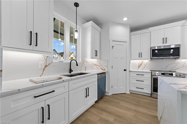 kitchen featuring white cabinetry, sink, stainless steel appliances, light hardwood / wood-style flooring, and decorative backsplash