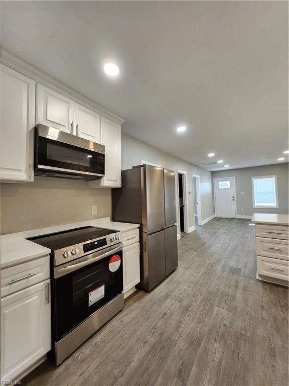 kitchen with appliances with stainless steel finishes, light wood-type flooring, and white cabinetry