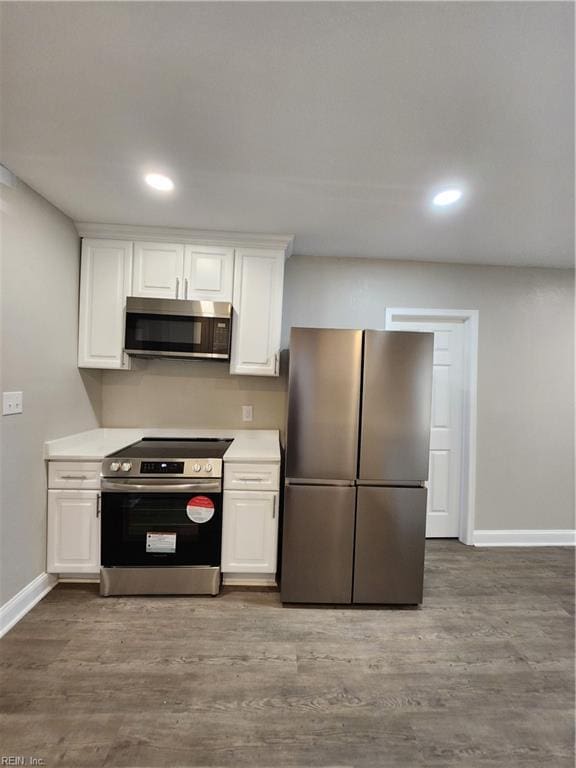 kitchen with white cabinets, appliances with stainless steel finishes, and wood-type flooring