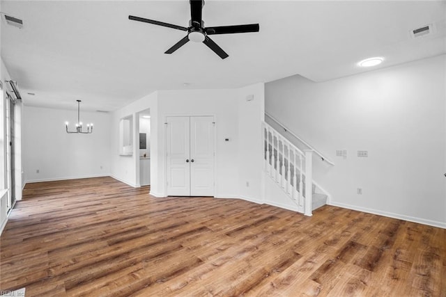 unfurnished living room with ceiling fan with notable chandelier and hardwood / wood-style flooring