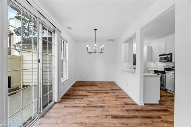 unfurnished dining area with a chandelier and light hardwood / wood-style flooring