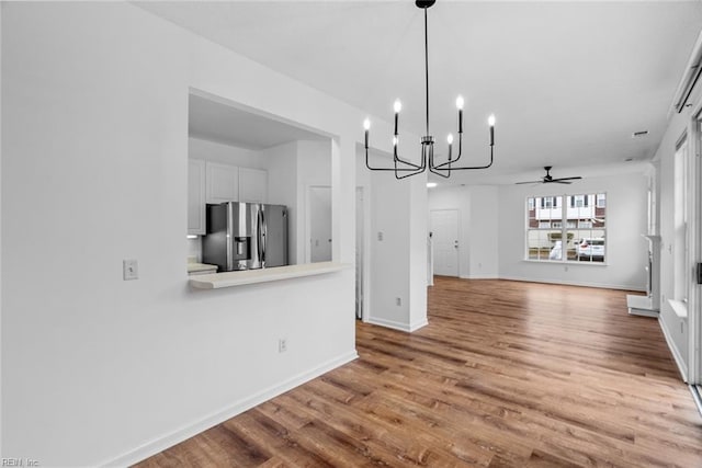 unfurnished dining area with hardwood / wood-style flooring and ceiling fan with notable chandelier