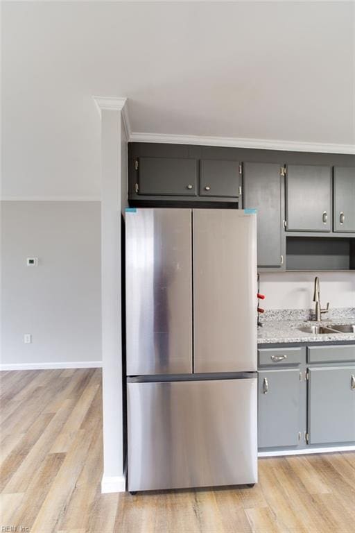 kitchen with stainless steel fridge, crown molding, sink, gray cabinets, and light hardwood / wood-style floors