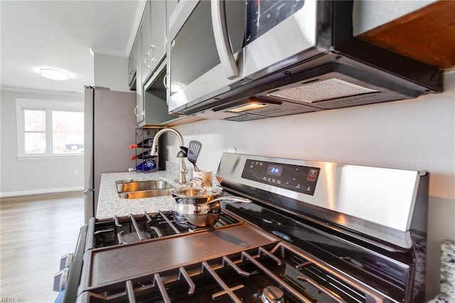 kitchen featuring hardwood / wood-style floors, stainless steel appliances, ornamental molding, and sink