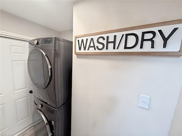 clothes washing area with stacked washing maching and dryer