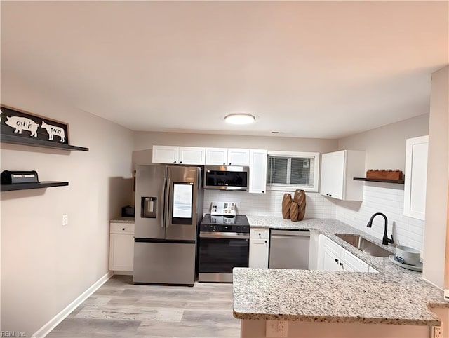 kitchen featuring backsplash, sink, white cabinetry, appliances with stainless steel finishes, and light stone counters