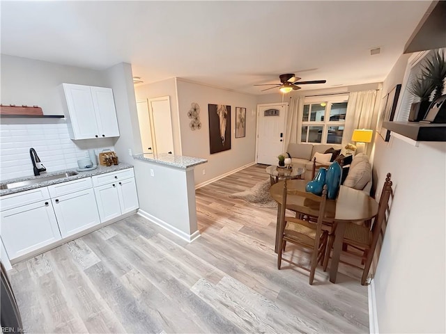 kitchen featuring light stone countertops, light hardwood / wood-style flooring, white cabinets, and sink