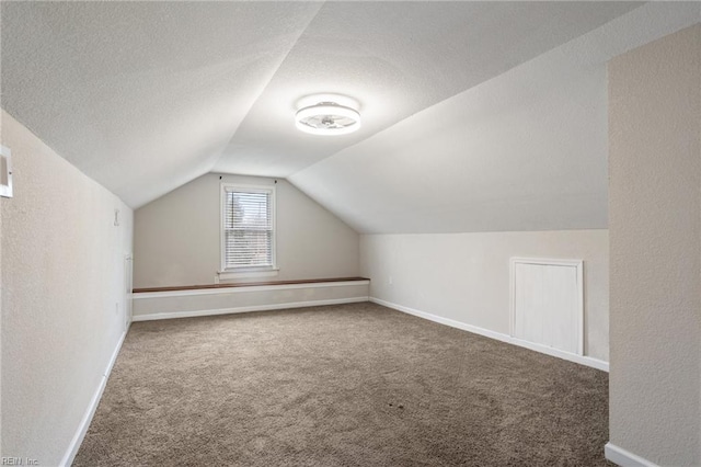 additional living space with vaulted ceiling, a textured ceiling, and dark carpet