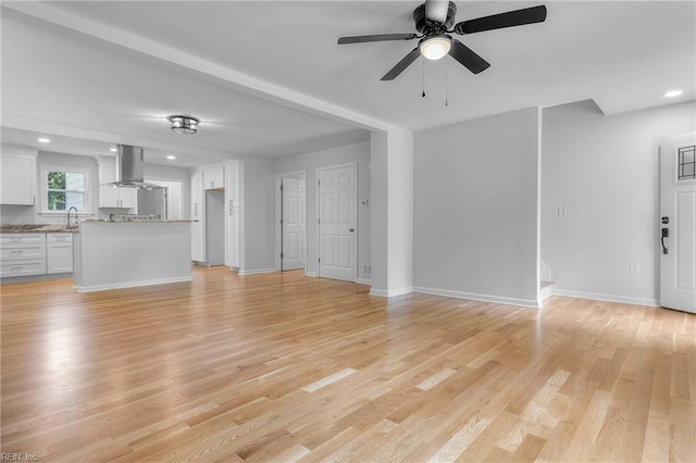 unfurnished living room with ceiling fan, light hardwood / wood-style floors, and sink