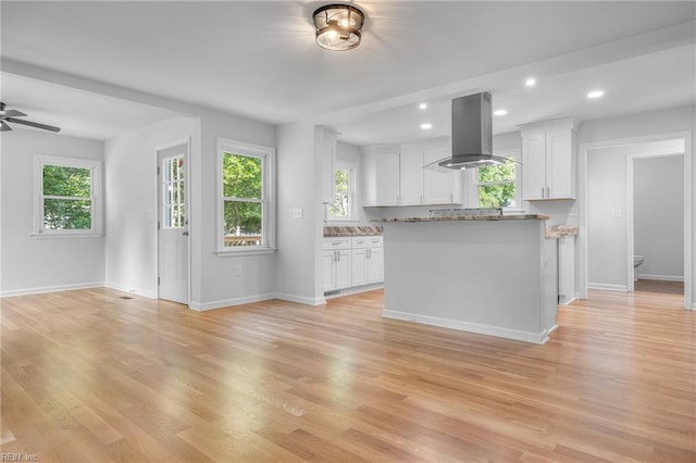 kitchen featuring white cabinetry, island range hood, light hardwood / wood-style floors, and light stone counters