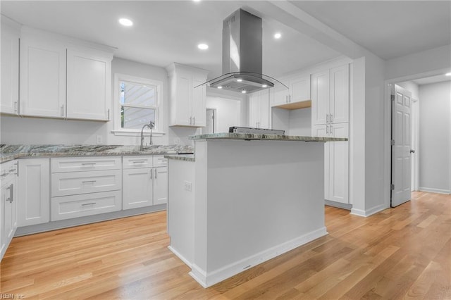 kitchen featuring white cabinets, island range hood, and light wood-type flooring