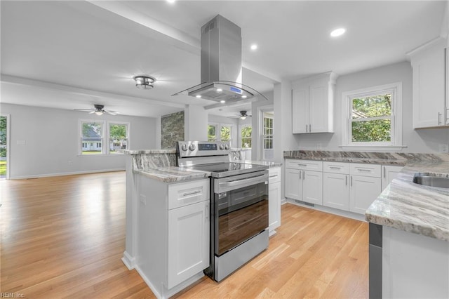 kitchen featuring island exhaust hood, white cabinetry, and stainless steel electric range oven