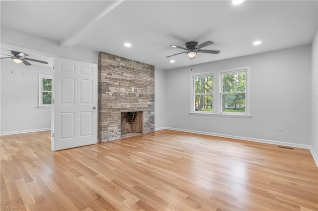 unfurnished living room featuring a stone fireplace, ceiling fan, and light hardwood / wood-style flooring