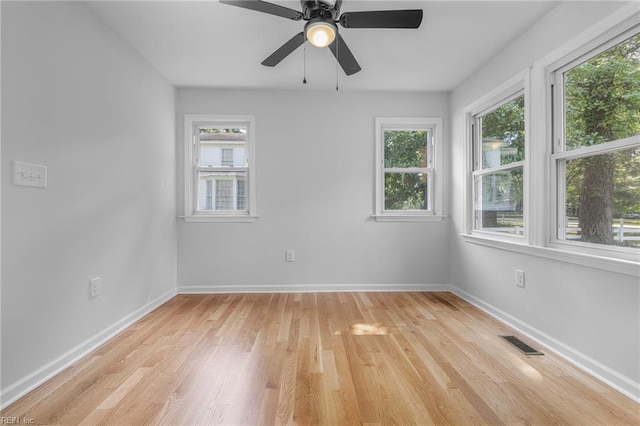 spare room featuring light wood-type flooring, a wealth of natural light, and ceiling fan