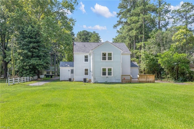 rear view of property featuring a lawn, cooling unit, and a deck