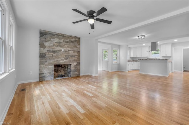 unfurnished living room featuring ceiling fan, a fireplace, and light hardwood / wood-style floors