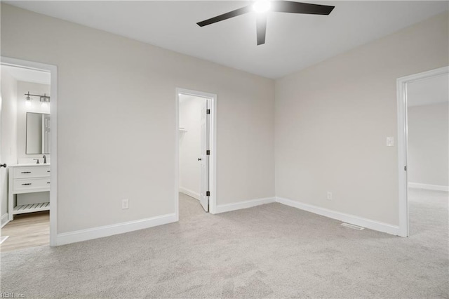 unfurnished bedroom featuring light carpet, connected bathroom, a spacious closet, and ceiling fan