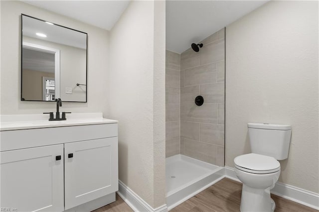 bathroom featuring tiled shower, wood-type flooring, vanity, and toilet