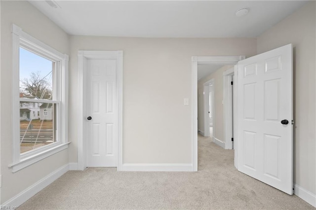 unfurnished bedroom with light carpet and a closet