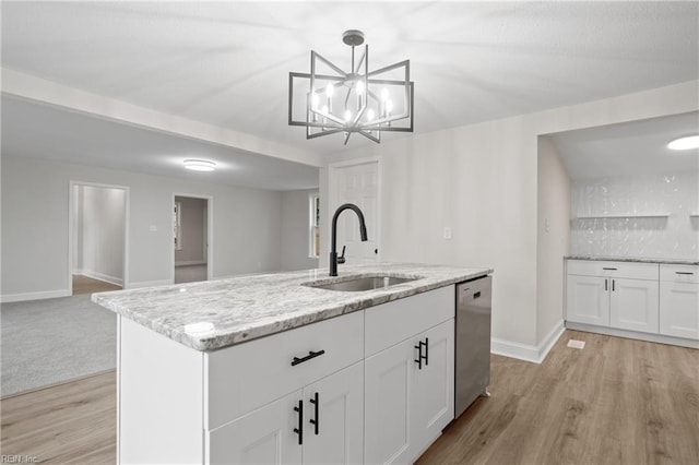 kitchen with stainless steel dishwasher, white cabinets, sink, and an island with sink