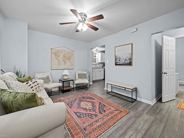 living room featuring ceiling fan, sink, and dark hardwood / wood-style floors