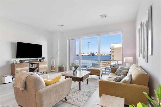 living room with a water view and light hardwood / wood-style floors