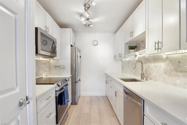 kitchen featuring backsplash, stainless steel appliances, white cabinetry, and sink