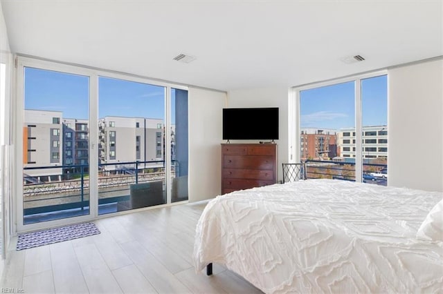 bedroom with light wood-type flooring and a wall of windows