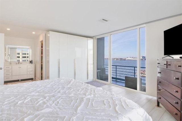 bedroom with access to exterior, expansive windows, light hardwood / wood-style flooring, and multiple windows