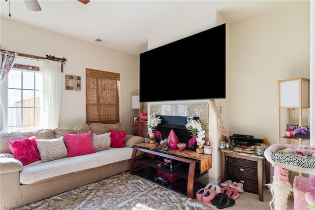 living room with a tile fireplace and ceiling fan